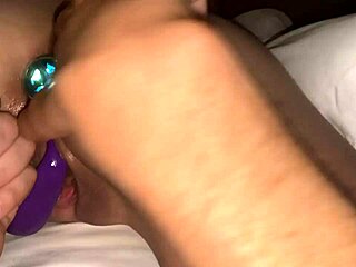 Hot chick with buttplug plays with toys on shaved pussy