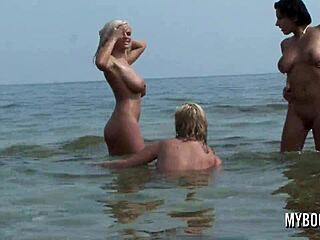 Drie blonde babes strippen naakt op een openbaar strand in Europa