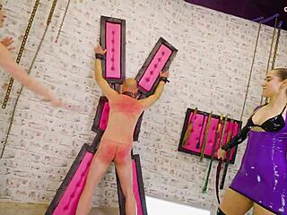 two fierce dominatrixes chain up slaves for spanking whipping session