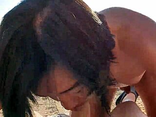 White man is deepthroating a nude Asian man on a Mediterranean beach